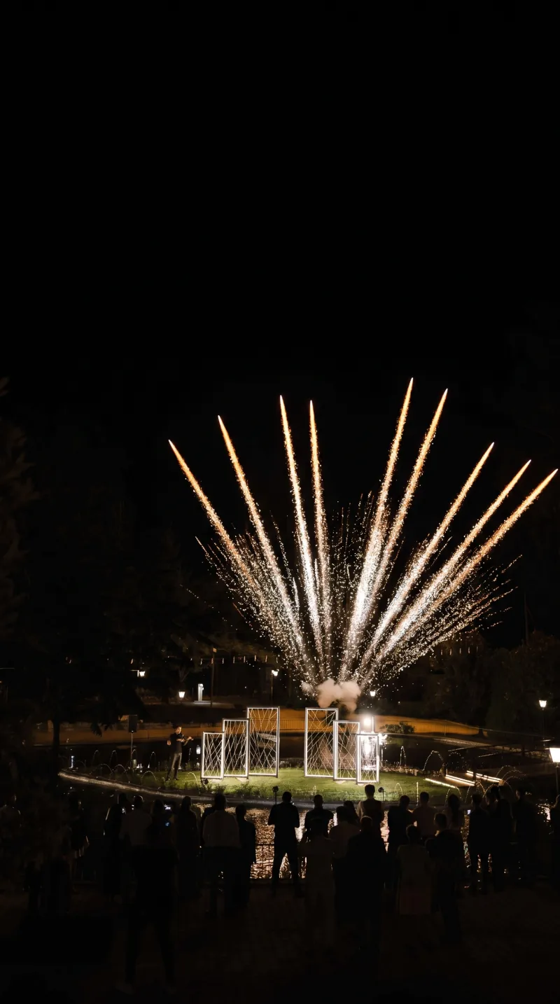 Imagem conceptual gerada por IA: fogo de artifício, cenário e convidados numa celebração noturna